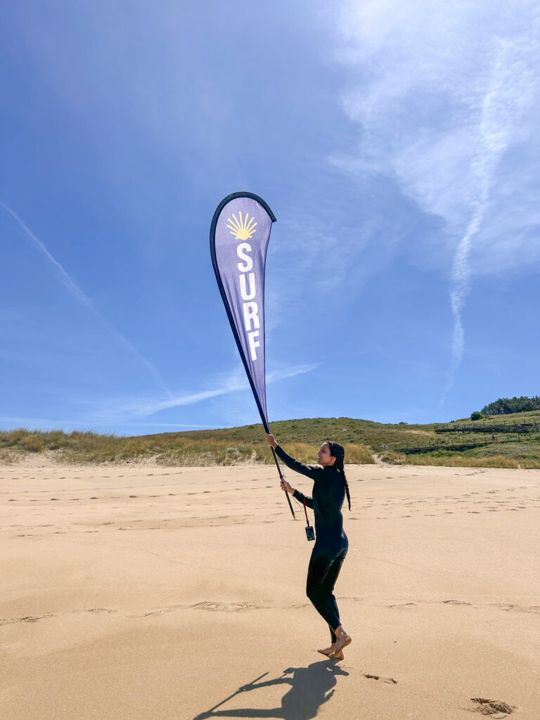 Una alumna de la Eric Rebière Surf Academy colocando la banderola en la playa de Mar de Fora